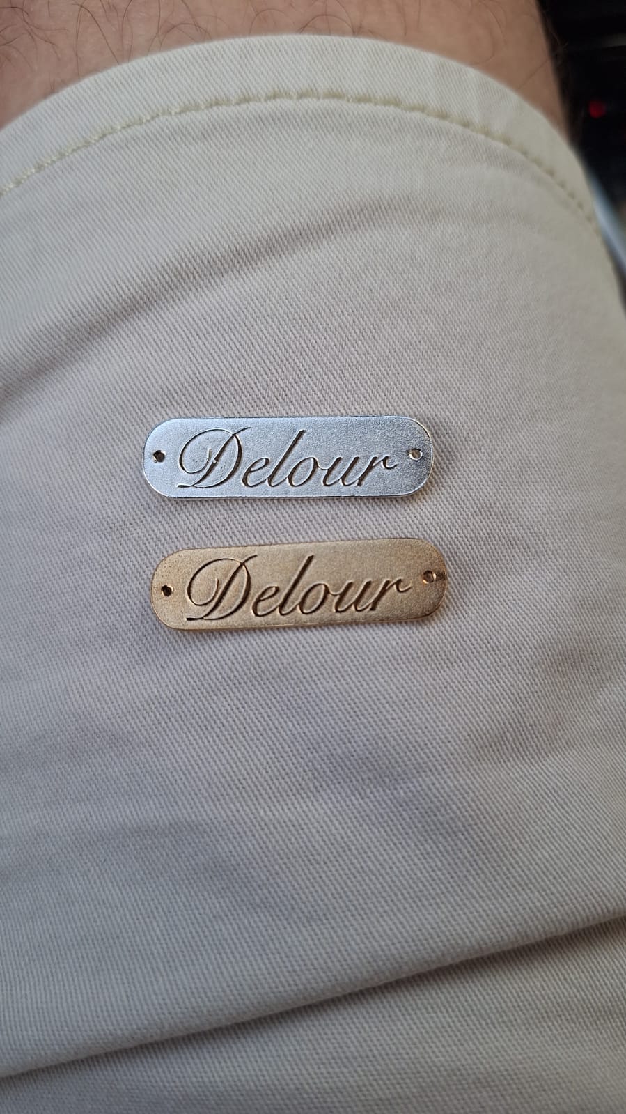 The Delour metal tags in silver and gold, attached to each handmade bag